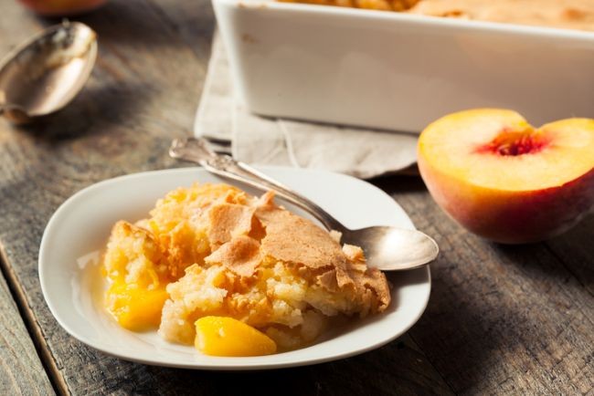bol alb cu crumble de piersici alalturi de fructe si tava la exterior