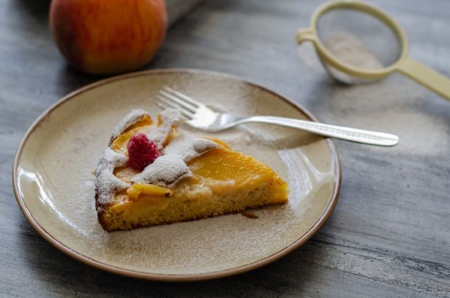 imagine cu felie de tarta cu piersici pe farfurie si cu furculita