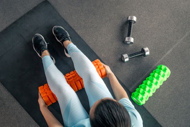 fata la sala cu foam rollers in costum de sport