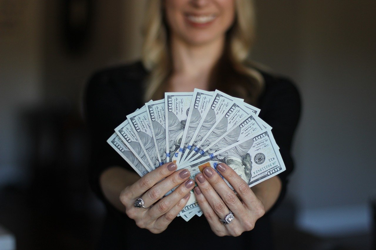 femeie care tine bani in mana in forma de evantai