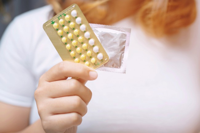 femeie care tina in mana o folie de pilule contraceptive