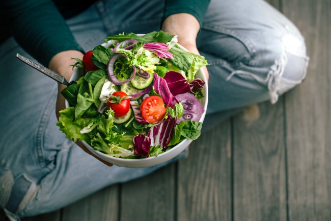 femeie care mananca o salata cu legume de sezon