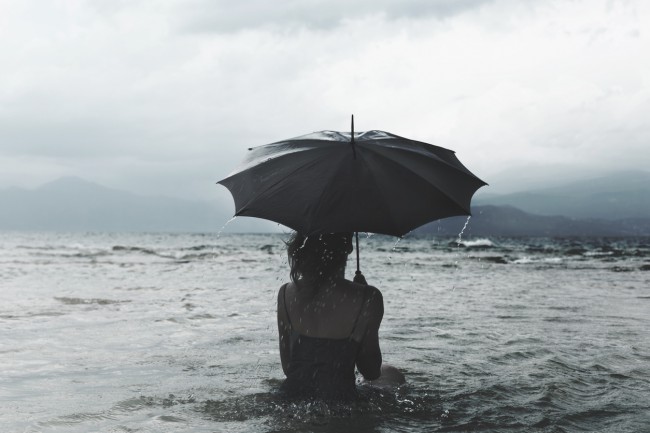Femeie în apă cu umbrelă deasupra capului
