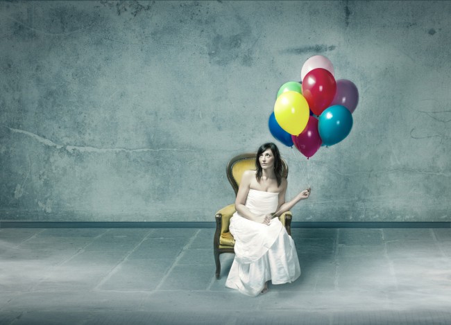 Femeie așezată pe scaun cu baloane în mână