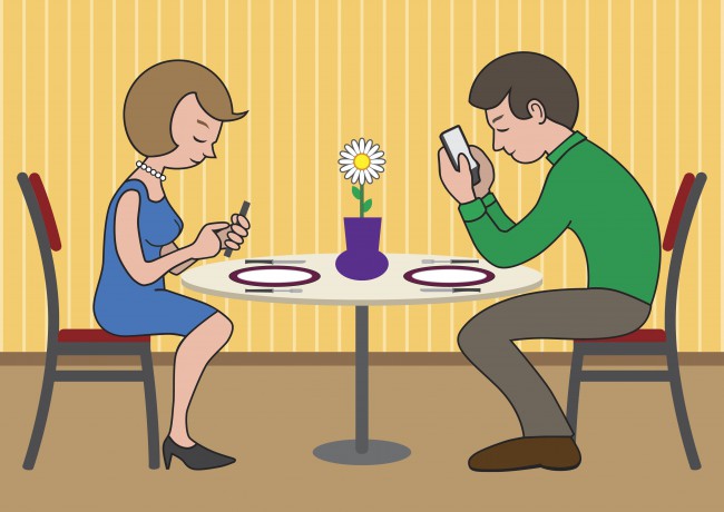 Femeie și bărbat la masă cu ochii în telefon