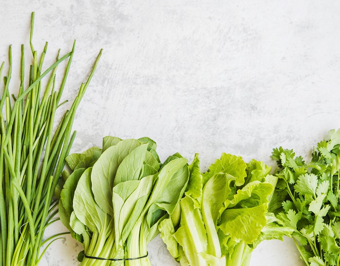 ceapa verde, salata verde, patrunjel si alte verdeturi asezate pe un blat