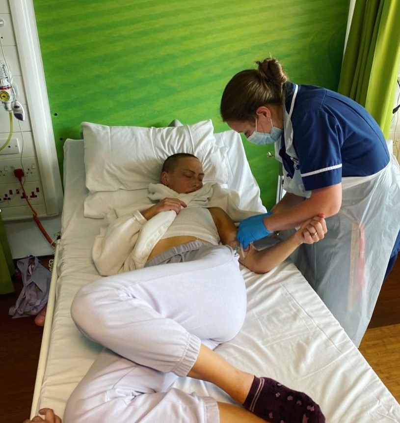 Instructorul fitness, Lily, pe patul de spital administrându-și tratamentul de chimioterapie cu ajutorul unei asistente medicale