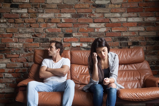 Cuplu de tineri stând supărați pe o canapea