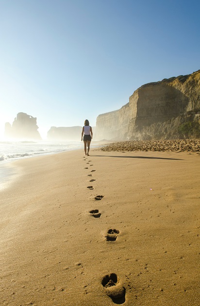 Urme de pași lăsate de o tânără care se plimbă pe o plajă pustie