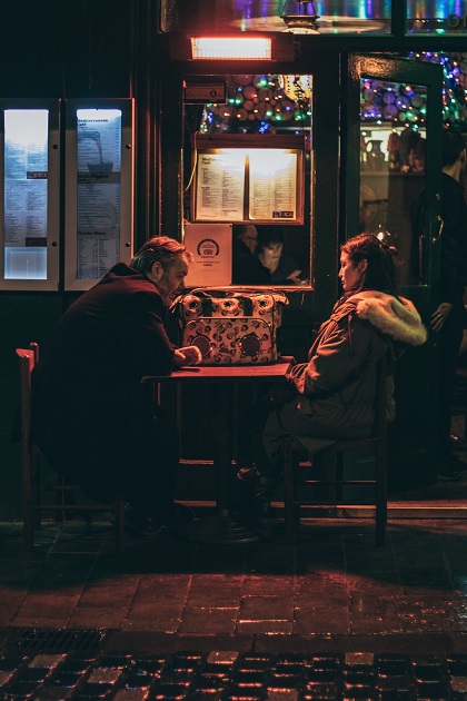 Un bărbat și o femeie supărați stând la masa unui local  slab luminat.