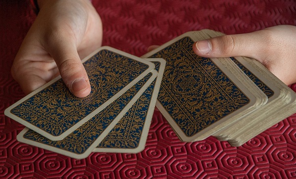 femeie ofera carti de tarot de ales pe o suprafara rosie