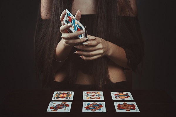 femeie in bluza neagra si cu unghiile facute cu alb  etaleaza carti de tarot