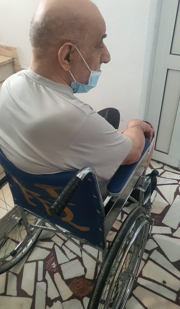 viorel lis in scaun cu rotile acasa asezat cu spatele cu masca la gura