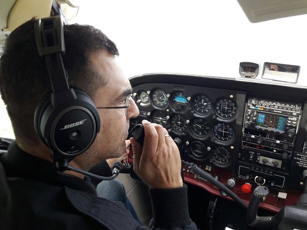 mihai margineanu la bordul unui avion cu casti pe urechi si microfon in mana