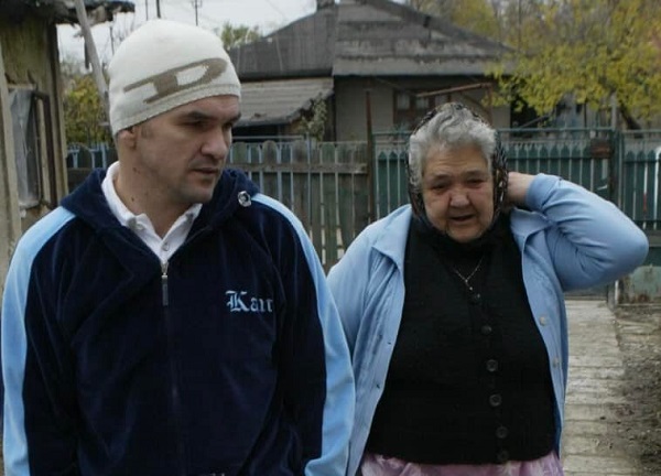 leonard doroftei impreuna cu mama lui pe batatura, femeia este imbracata in albastru el nu se uita la camera