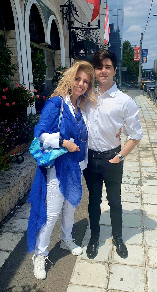 bianca brad imbracata in albastru alaturi de fiul ei luca in camasa alba pe strada