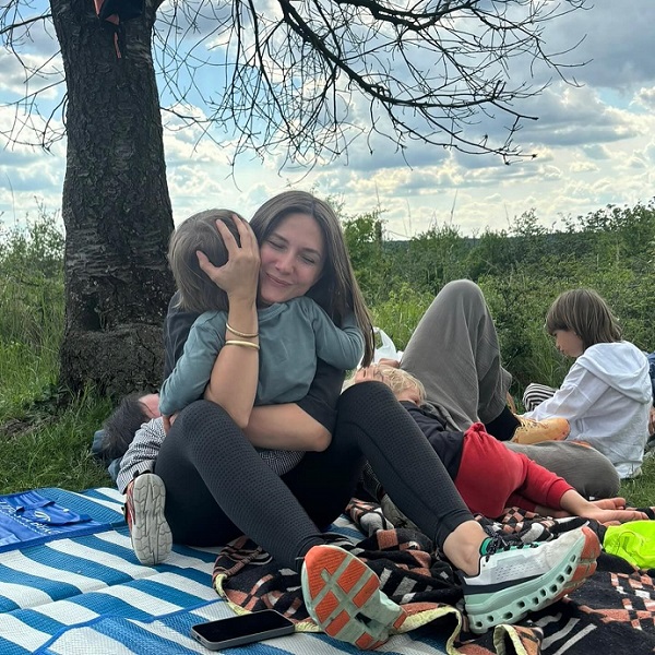 adela popescu isi tine in brate unul din copii aflandu-se la picnic la iarba verde