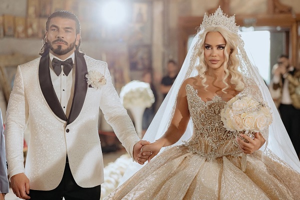 anda adam in rochie de mireasa cu buchet de flori in mana alaturi de sotul ei in costum alb negru