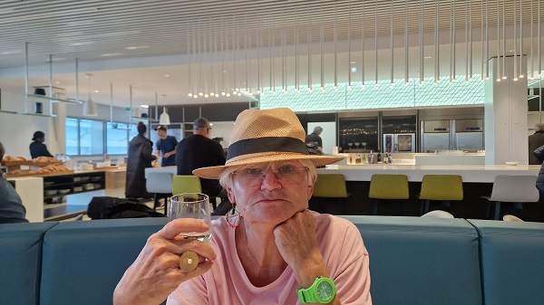 monica tatoiu la o masa pe o canapea albastra cu pahar de vin alb in mana