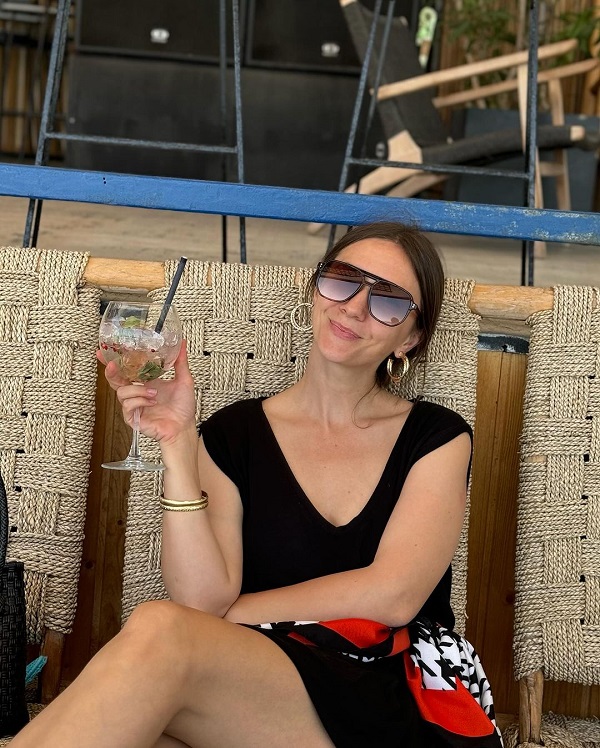 adela popescu cu rochie neagra si pahar cu cocktail in mana pe un sezlong
