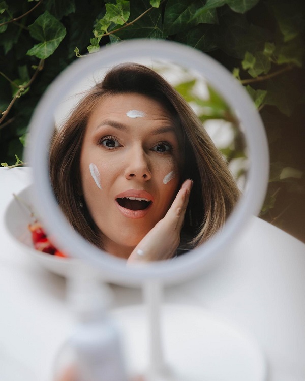 adela popescu se uita in oglinda rotunda si se da cu crema pe fata
