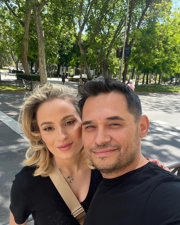 mihai rait si sotia lui pe strada in spate un loc inverzit amandoi sunt imbracati in negru ana maria are parul cu bucle