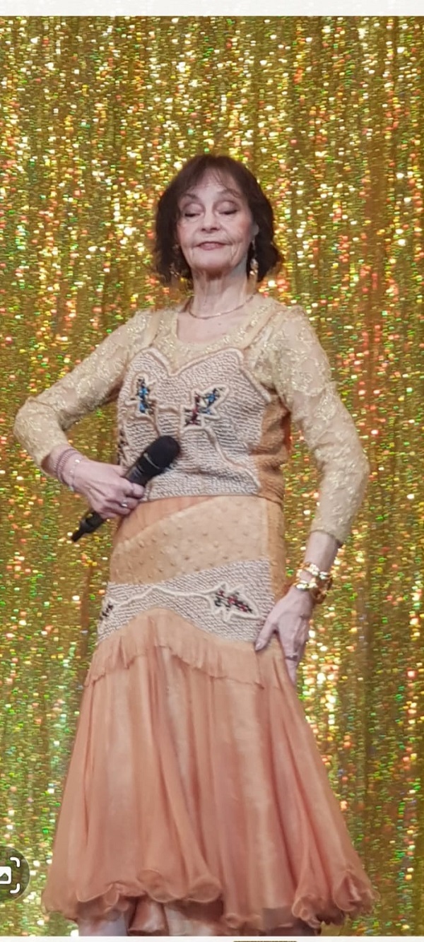 marina voica imbracata in rochie roz pe scena cu microfon in mana danseaza