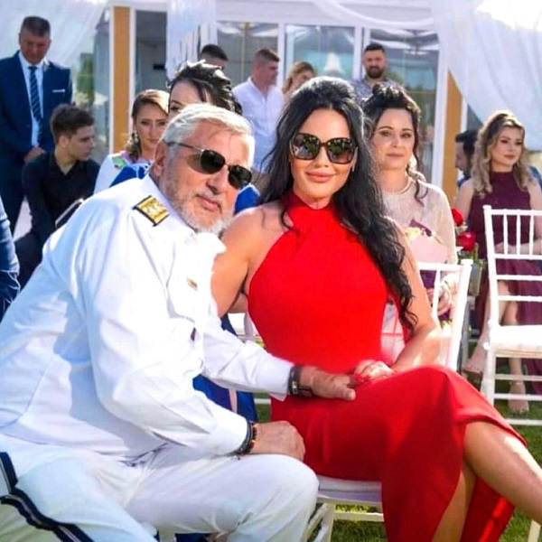 ilie nastase imbracat in alb sta pe scaun alaturi de sotia lui ioana nastase in rosu cu ochelari la ochi