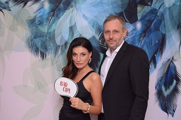 ioana ginghina imbracata in rochie neagra alaturi de cristi pitulice in costum negru pe fundal albastru la un eveniment