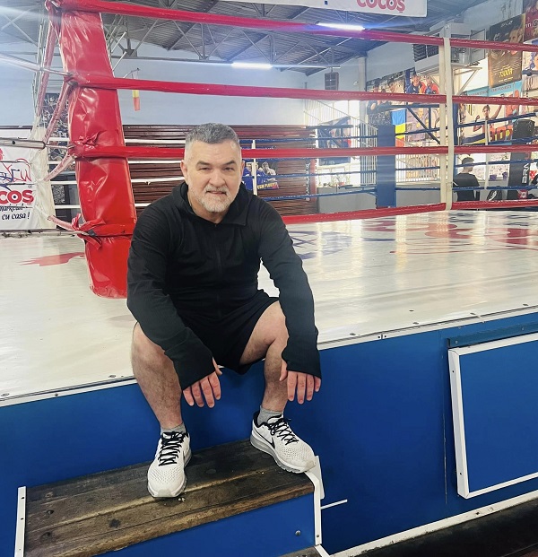 leonard doroftei in costum negru sta pe treptele unei sali de box