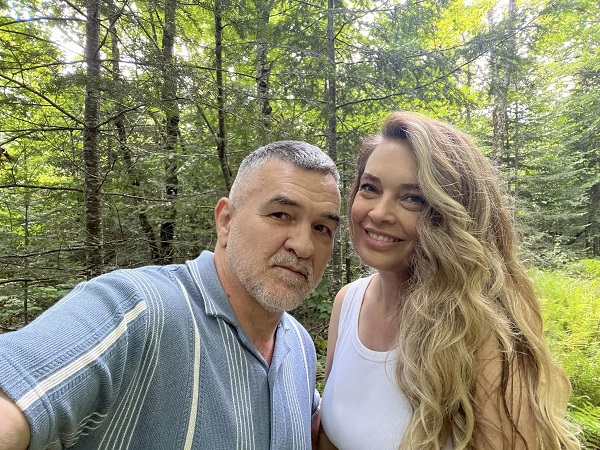 leonard doroftei imbracat in camasa albastra alaturi de sotia lui imbracata in maieu alb in padure