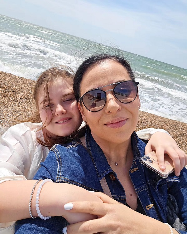 oana roman cu ochelari la ochi face selfie cu fiica ei tinand-o in brate la mare
