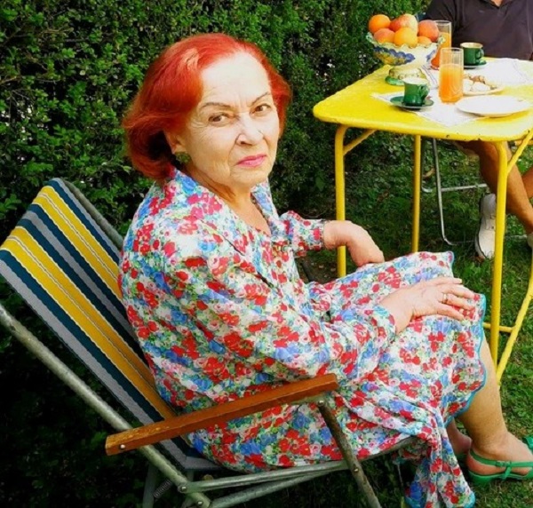 sanda taranu in rochie alba cu imprimeuri stand pe un sezlong colorat