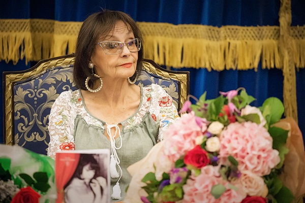marina voica cu ochelari la ochi la masa inconjurata de bujori roz