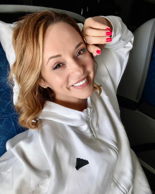 andreea marin cu parul lejer coafat si unghii rosii sta pe spate si zambeste