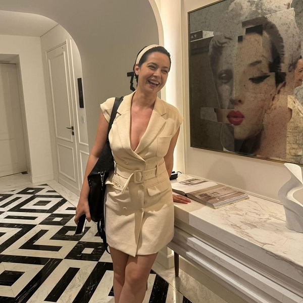 maria dinulescu langa un tablou la o expozitie de arta imbracata intr-un sarafan alb