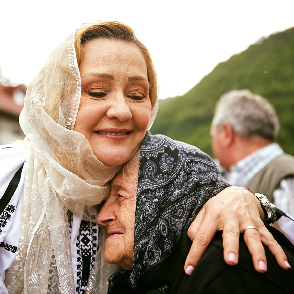 elena lasconi in costum popular cu marama pe cap imbratiseaza o batrana