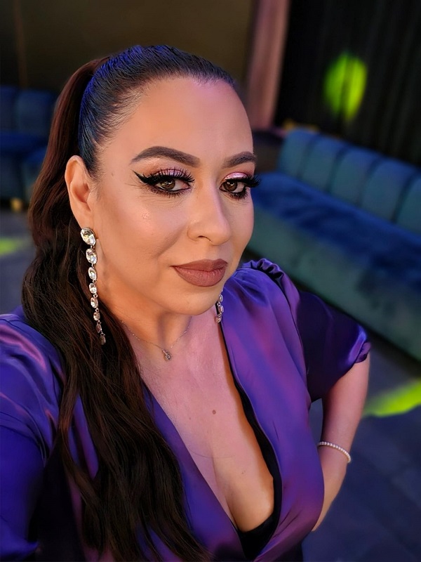 oana roman machiata si cu parul prins in coada imbracata in rochie mov isi face un selfie