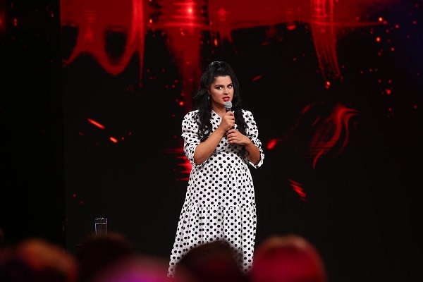 ioana state in rochie alba cu buline pe scena cu microfonul in mana