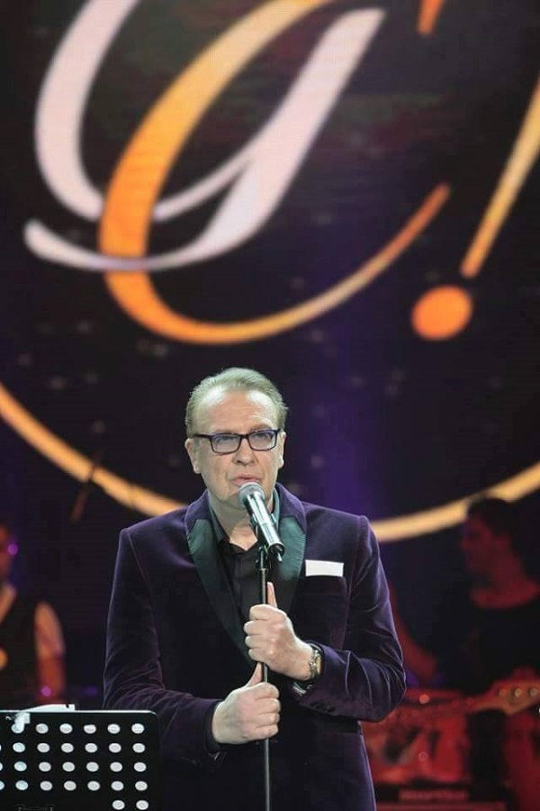 gabriel cotabita canta pe scena cu microfonul in mana si arata spre public