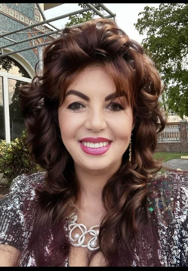 carmen harra cu parul facut bucle zambeste la camera imbracata in camasa cu model