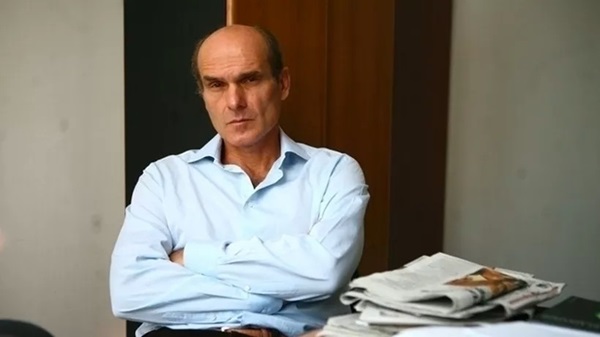 cristian tudor popescu imbracat in camasa bleu la birou sta cu mainile incrucisate