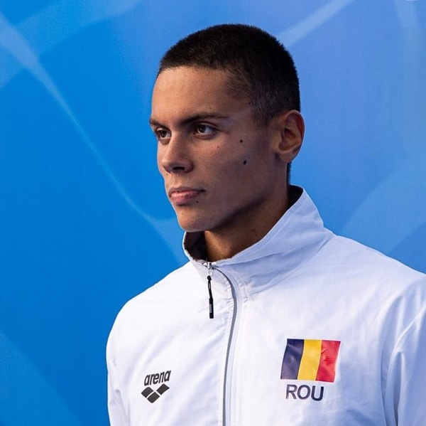 campionul la natatie david popovici imbracat in costum alb cu steagul romaniei