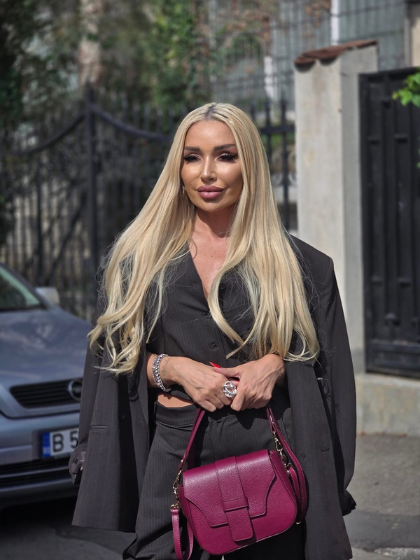 sonia trifan imbracata in negru cu parul aranjat tine in mana o geanta rosie