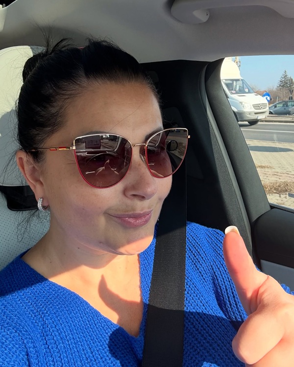gabriela cristea imbracata in tricou albastru cu ochelari de soare la ochi in masina face semnul ok