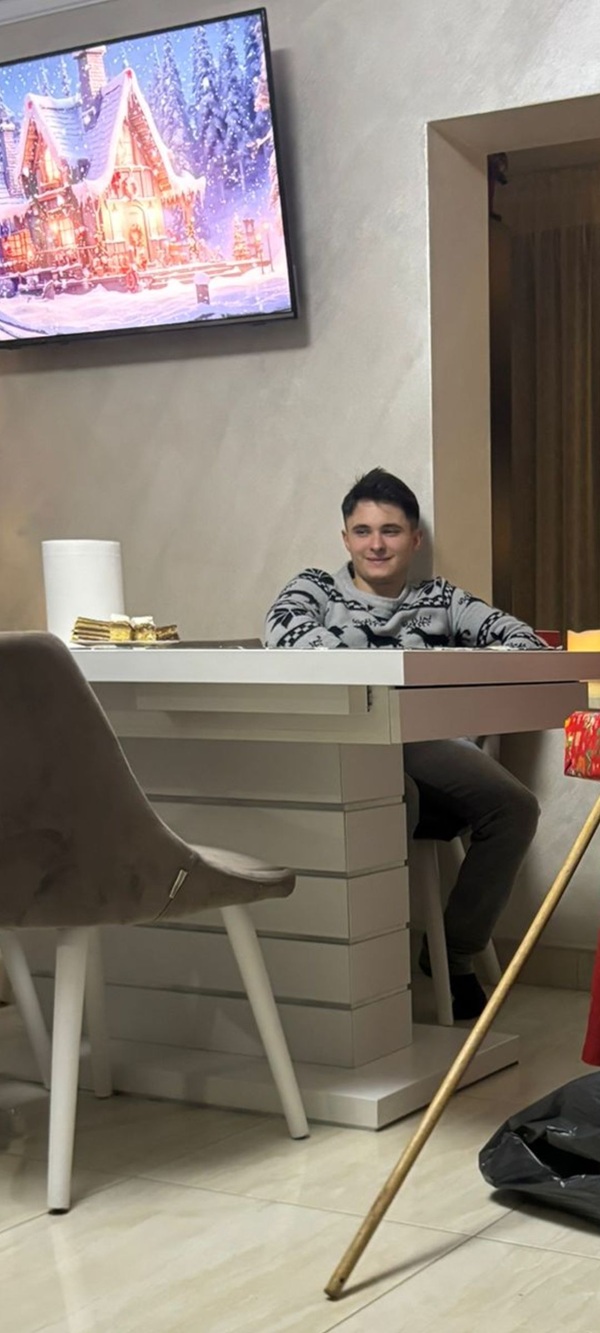baiat care sta pe un scaun in fata unei banci si rade