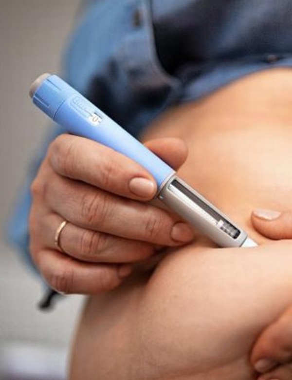femeie isi injecteaza in abdomen o sunstanta pentru slabit cu un dispozitiv de culoare albastra