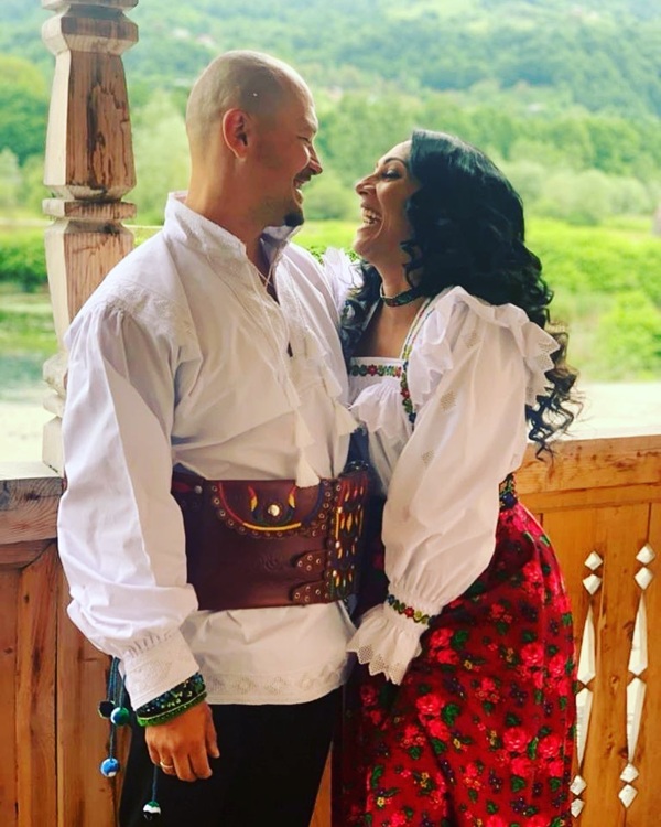 puya si sotia sa se privesc in ochi pe veranda unei case imbracati in costume populare