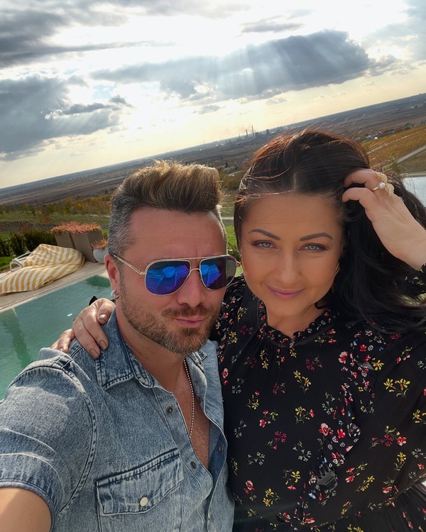 gabriela cristea isi trece mana prin par langa sotul ei cu ochelari de soare la ochi
