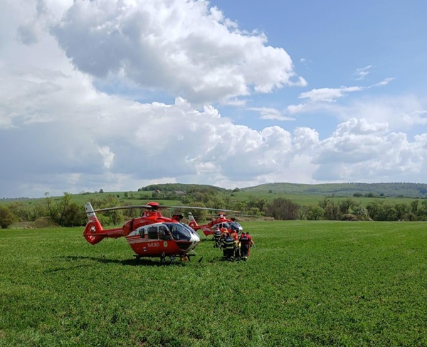 elicopter rosu smurd pe un camp cu mai multi pompieri care cara o victima